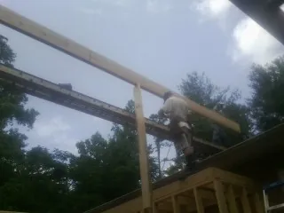 Carpenter setting a ridge beam over a new addition frame — Ice Dam Removal by Roofing Brothers in Belle