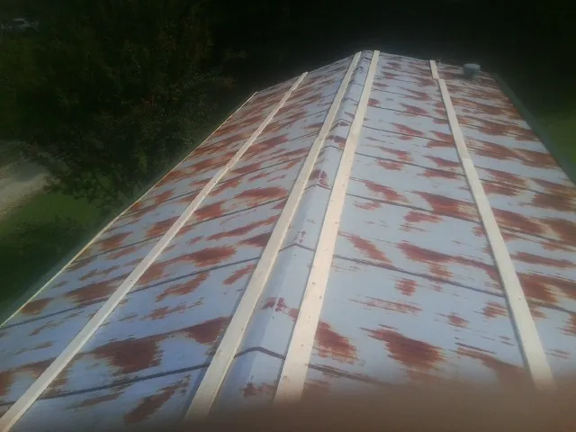 Rusted metal roof panels with new wood purlins before replacement — Storm Damage Roof Repair in Belle by Roofing Brothers