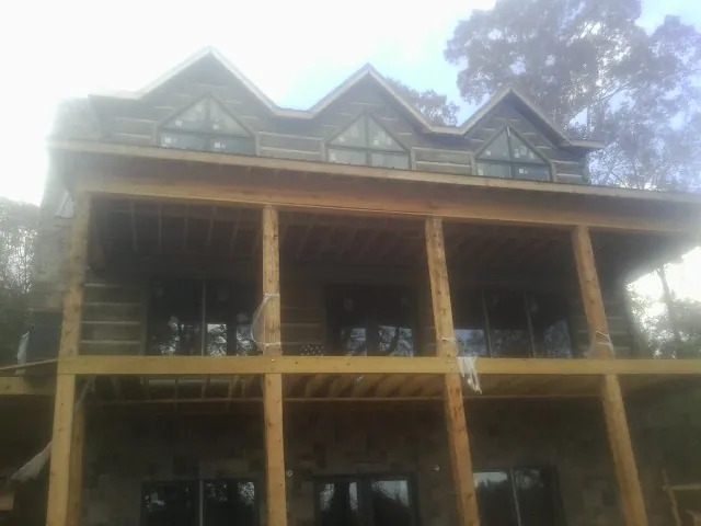 Dormers and porch framing on a large log home under construction — Roof Coating work by our crew in Belle