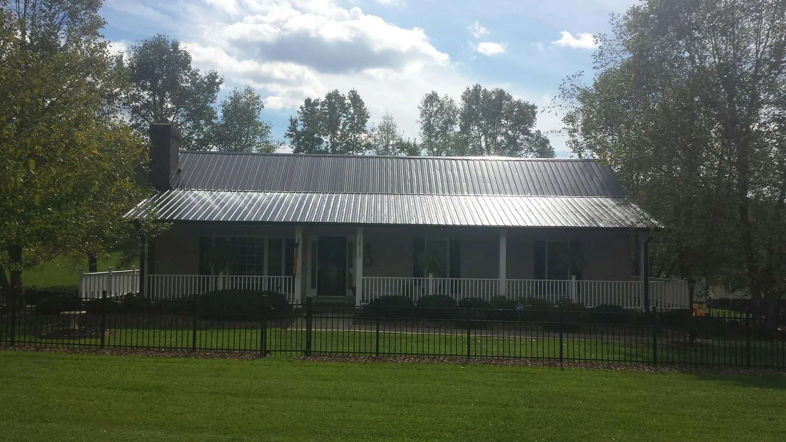 Gray metal roof on a brick ranch with a full width front porch — Gutter Guard Installation work by our crew in Belle