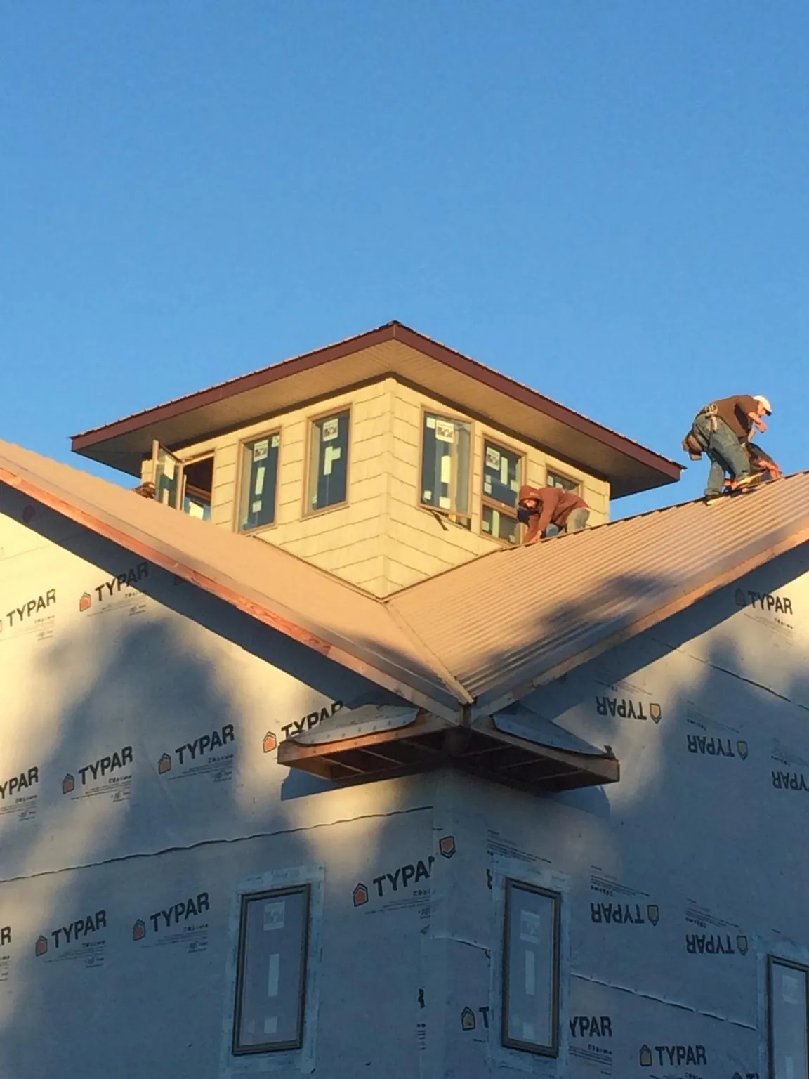 Roofers working around a rooftop cupola on a new metal roof at sunset — Roof Waterproofing in Belle by Roofing Brothers
